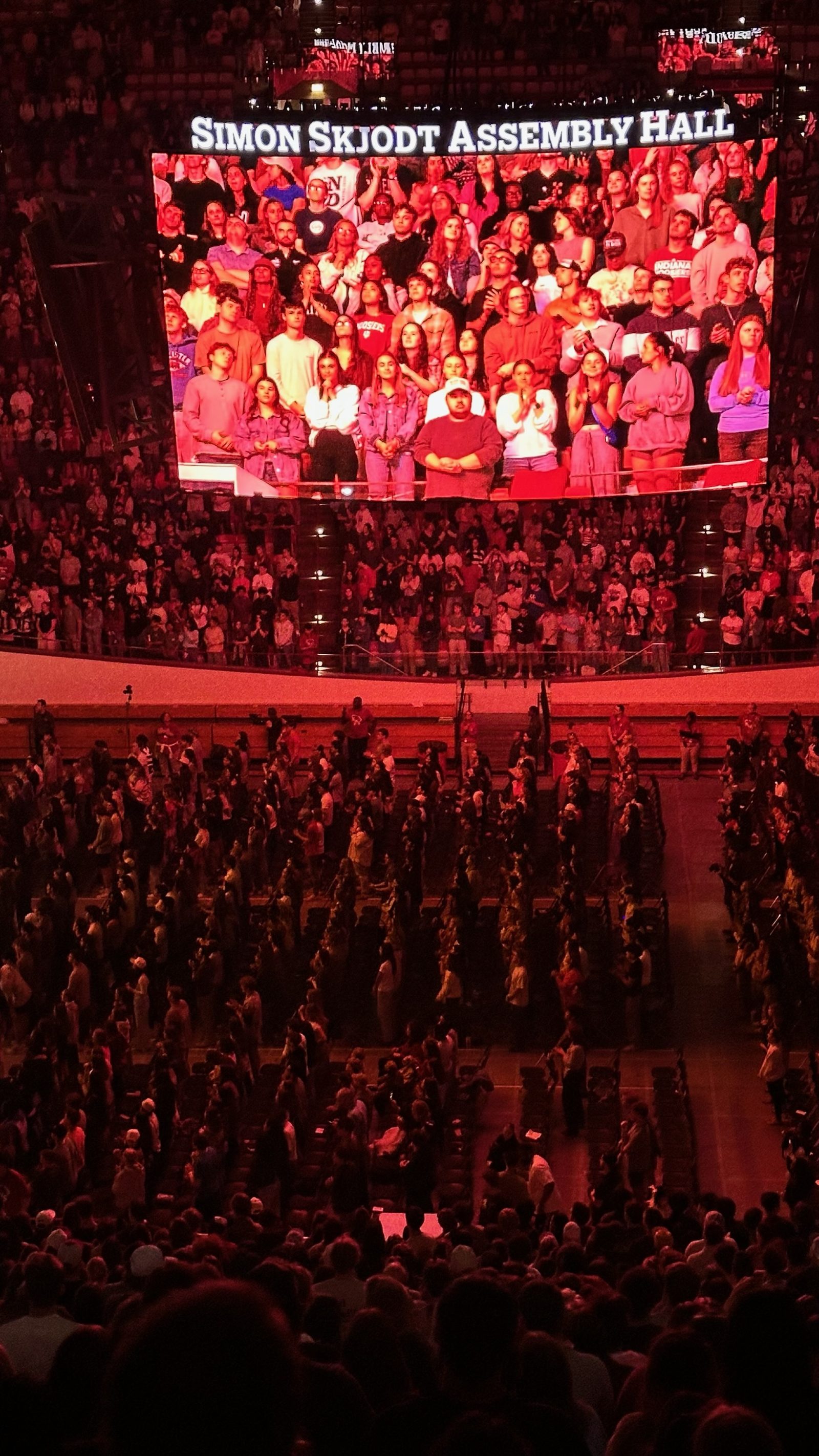 The video wall showing a live close-up of the student crowd under the venue nameplate